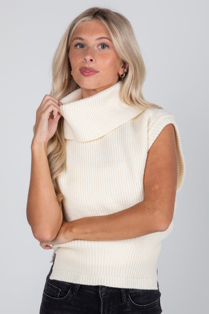 Woman wearing a cream sleeveless knitted vest against a plain background