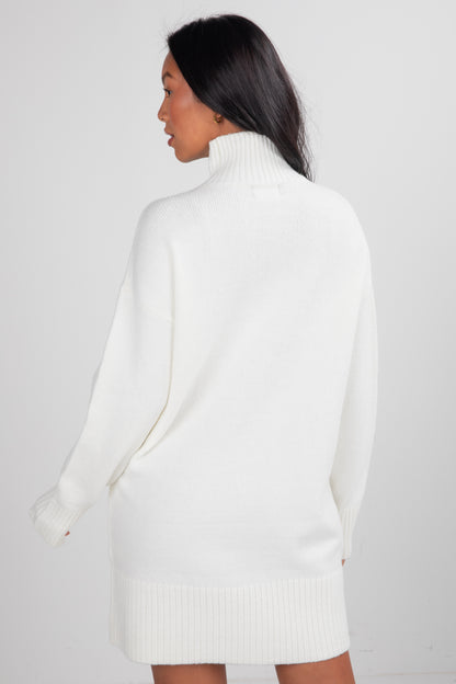 Woman wearing a white turtleneck sweater against a plain background