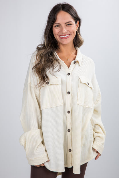 Woman wearing a cream-colored button-up shirt with a white background