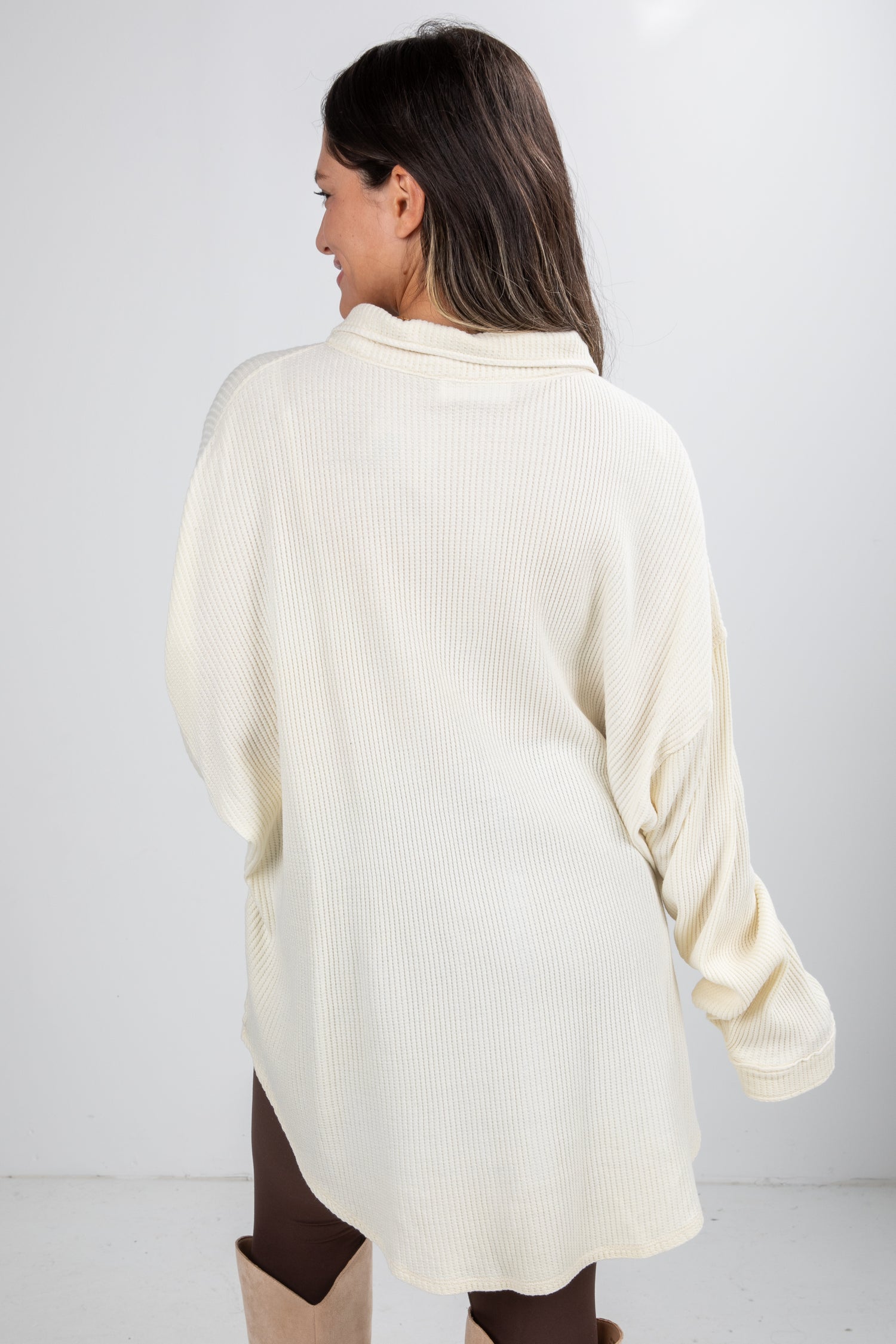 Woman wearing a cream-colored sweater against a white background