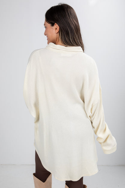 Woman wearing a cream-colored sweater against a white background