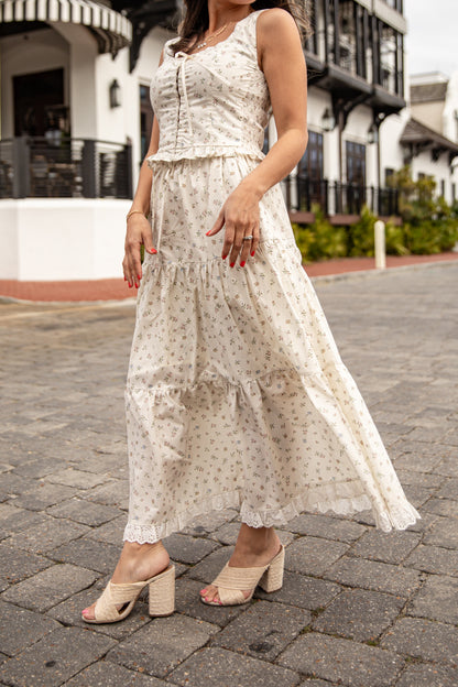 Woman wearing a white floral dress on a cobblestone street.