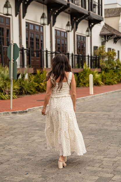 Woman in a white dress walking on a paved path with a building in the background