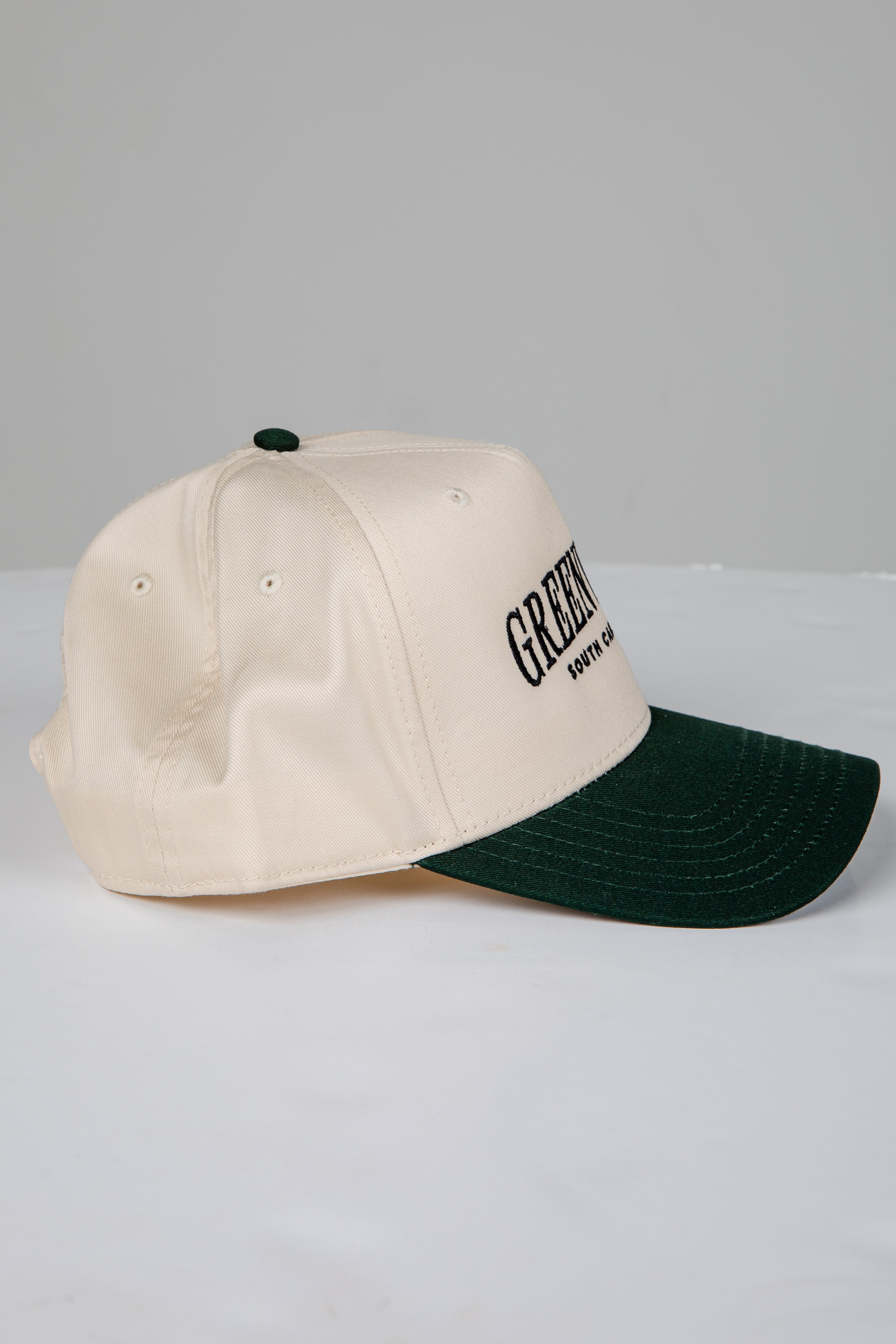 Two-tone cap with beige front and green back on a light gray background