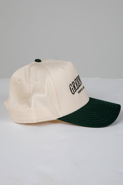 Two-tone cap with beige front and green back on a light gray background