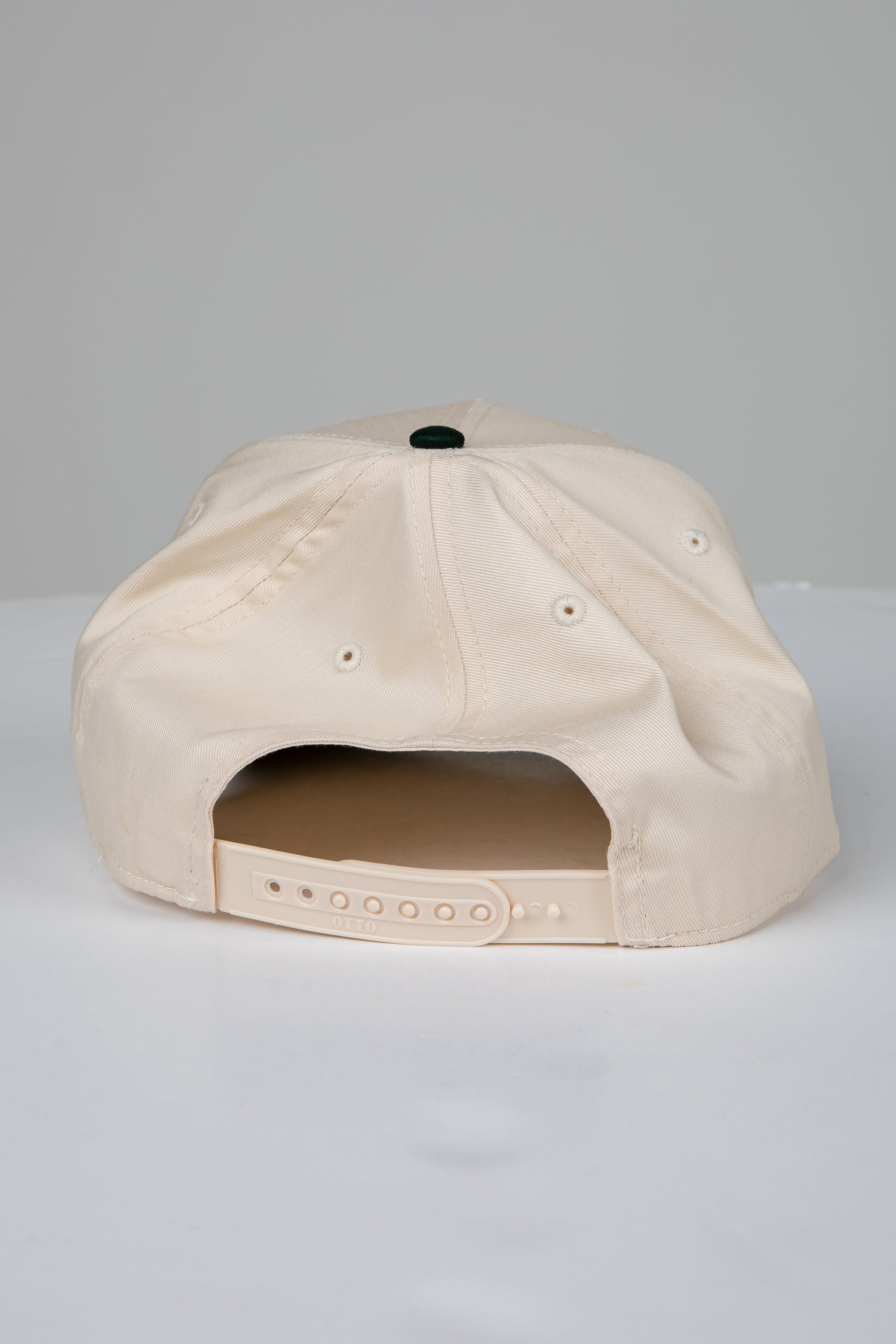 Beige cap with a black button on a light gray background