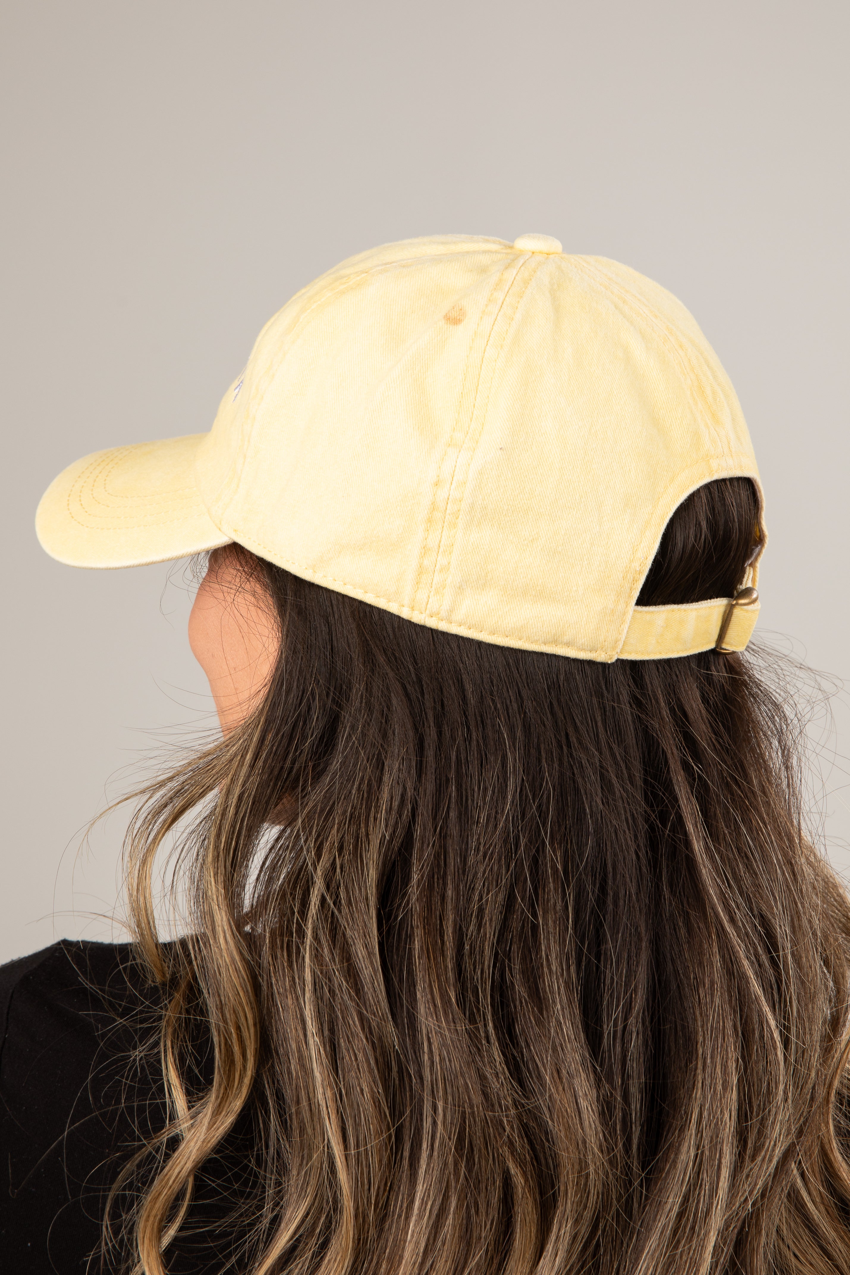 Person wearing a yellow baseball cap on a plain background