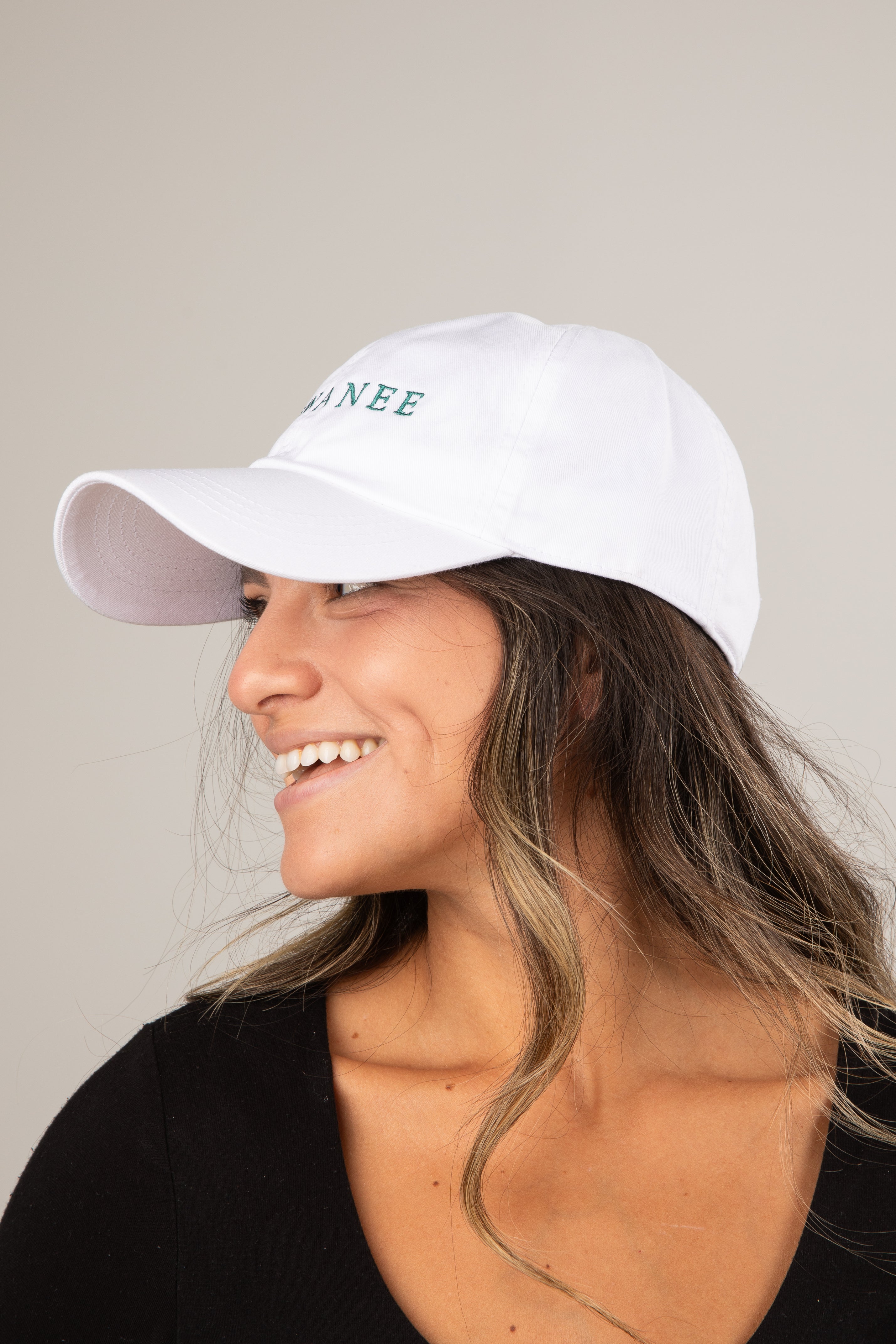 Woman wearing a white cap with text on a neutral background