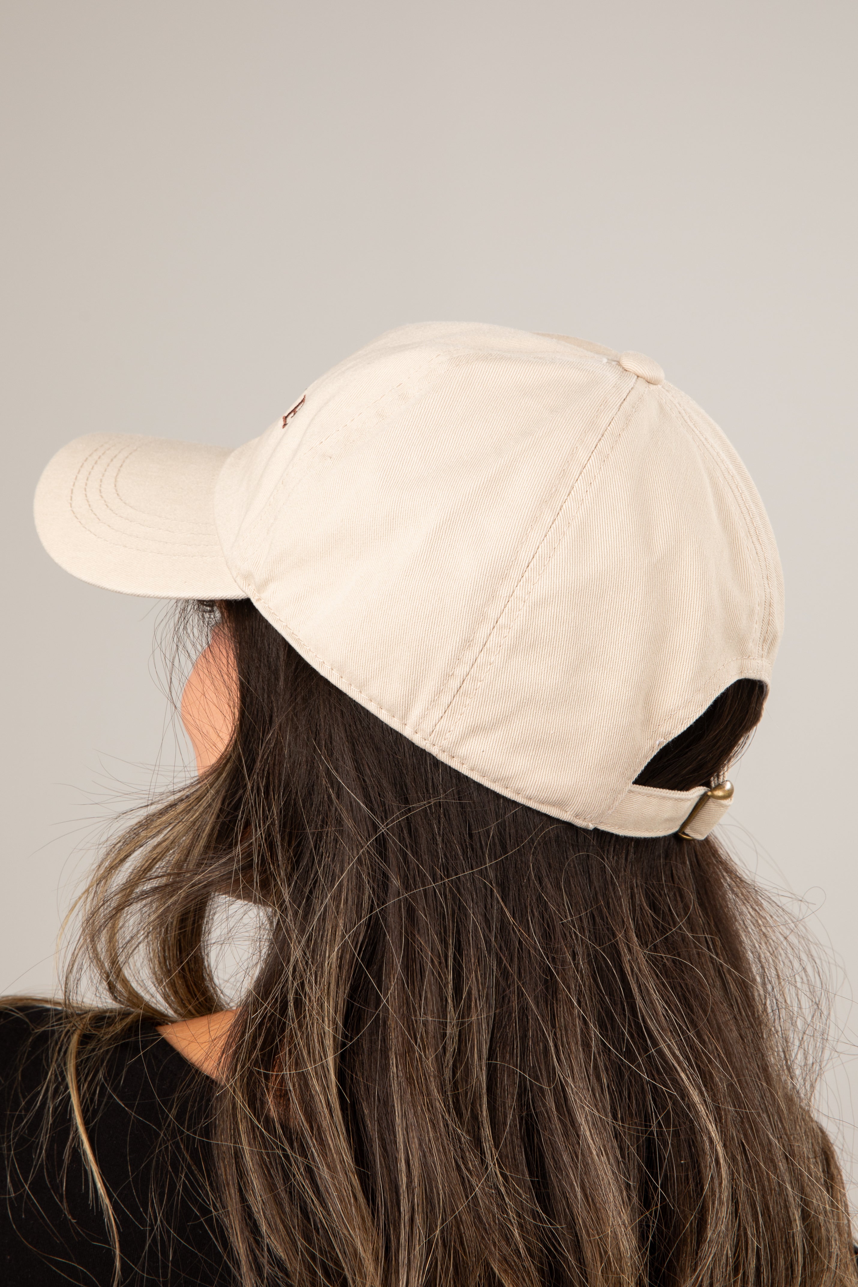Person wearing a beige baseball cap on a plain background
