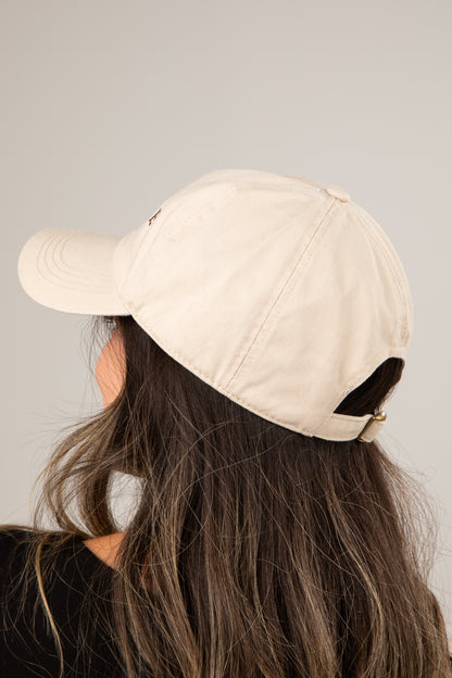 Person wearing a beige baseball cap on a plain background