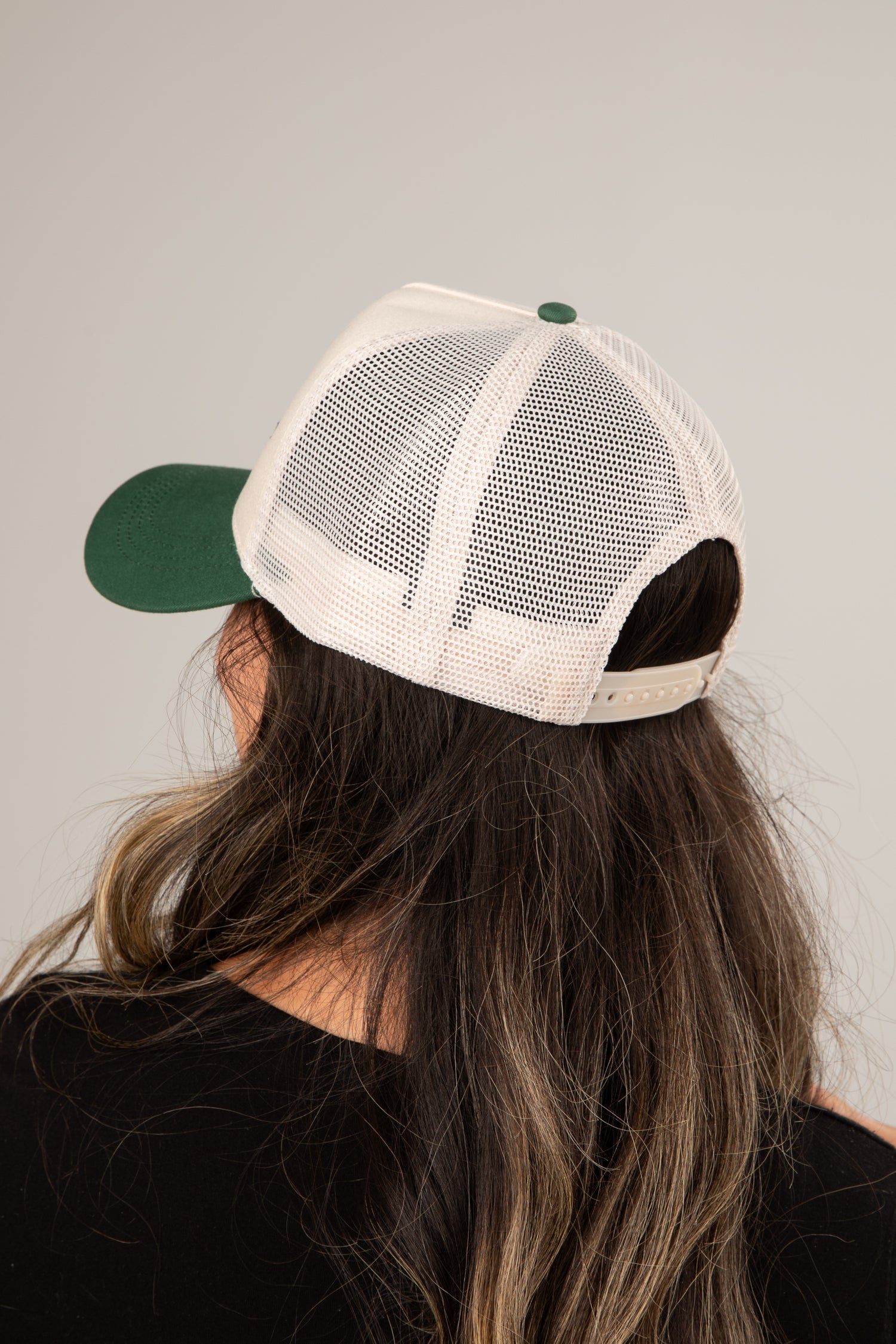 Person wearing a green and beige cap with a plain background