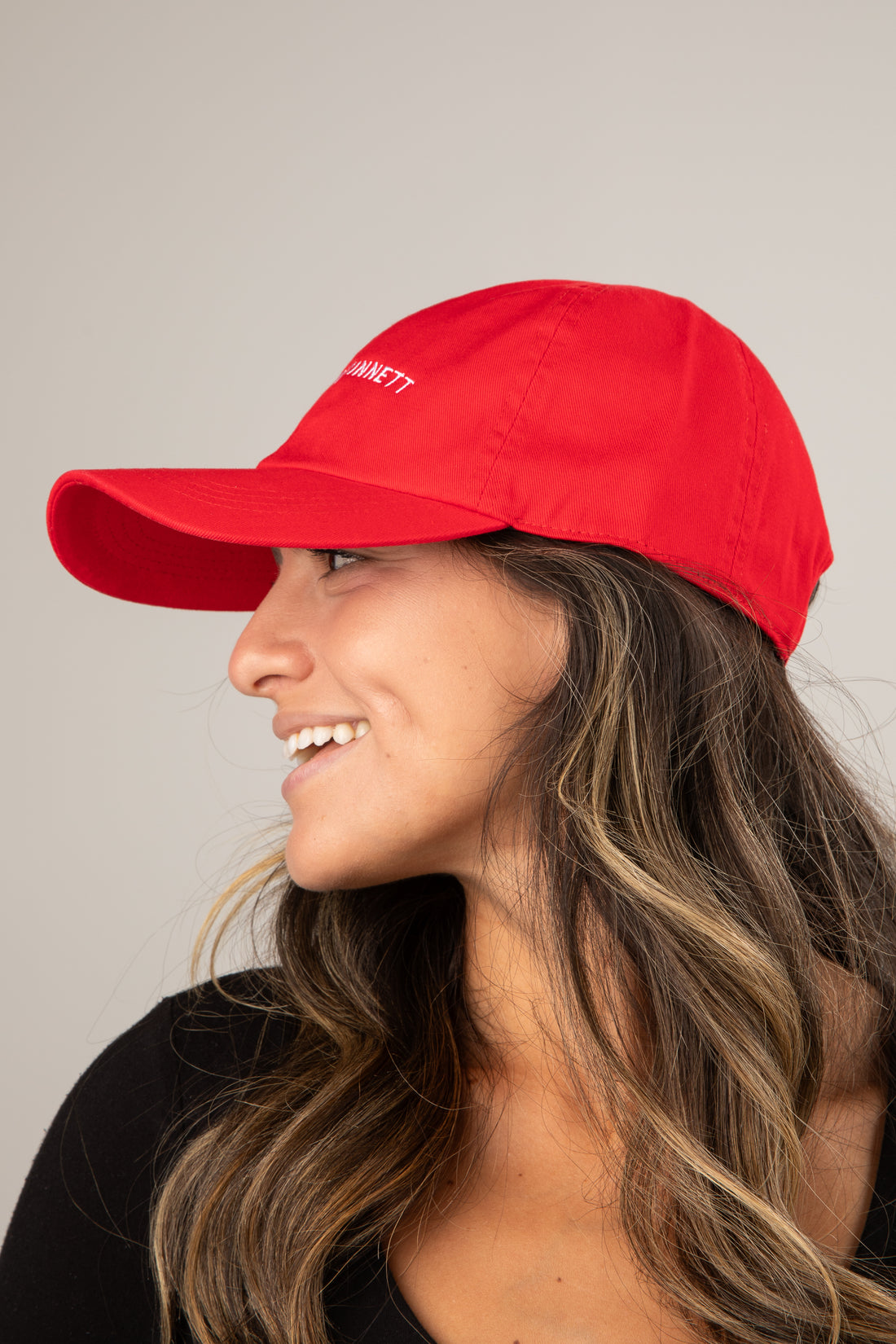 Woman wearing a red cap with a logo on a plain background