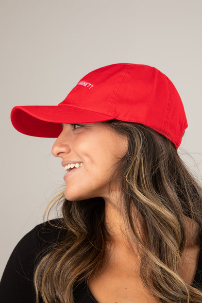 Woman wearing a red cap with a logo on a plain background