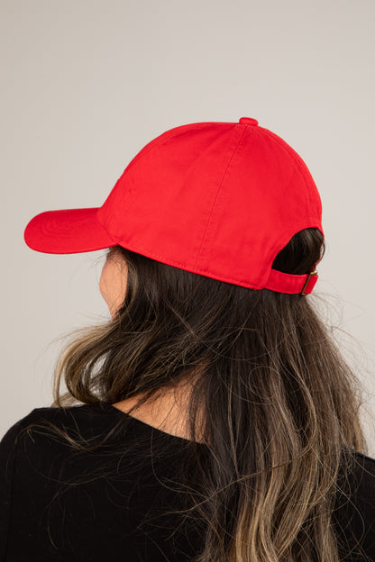 Person wearing a red cap from behind with a plain background