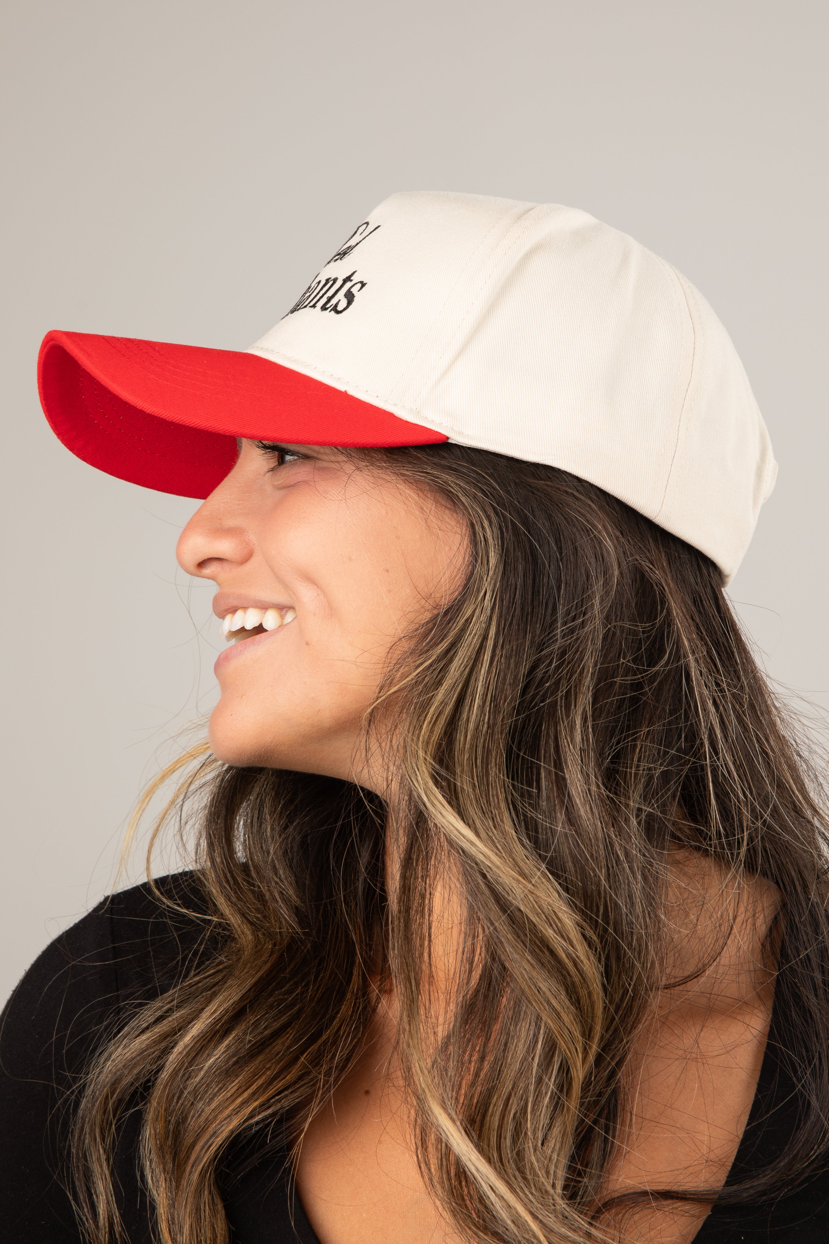 Woman wearing a white cap with a red brim on a gray background