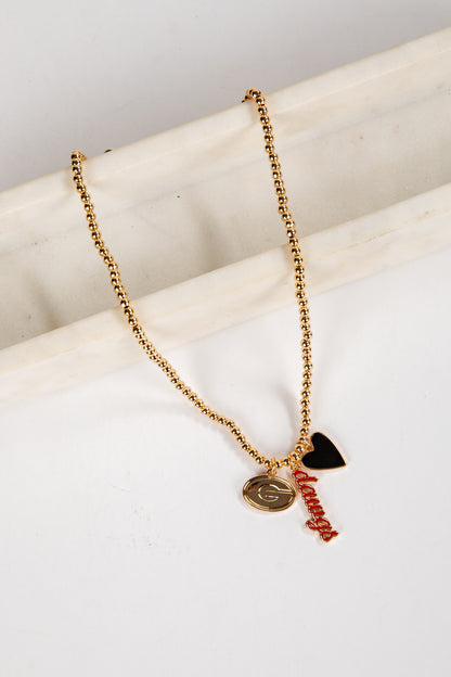 Gold necklace with heart and letter pendant on a white surface