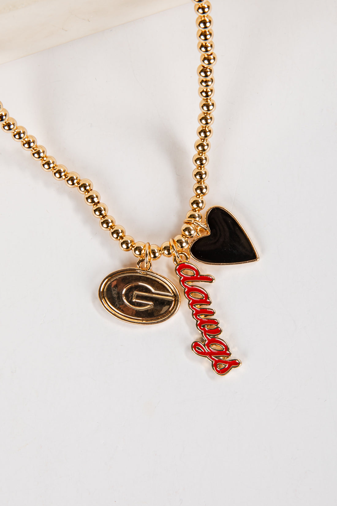 Necklace with gold beads, a heart-shaped black pendant, and red &