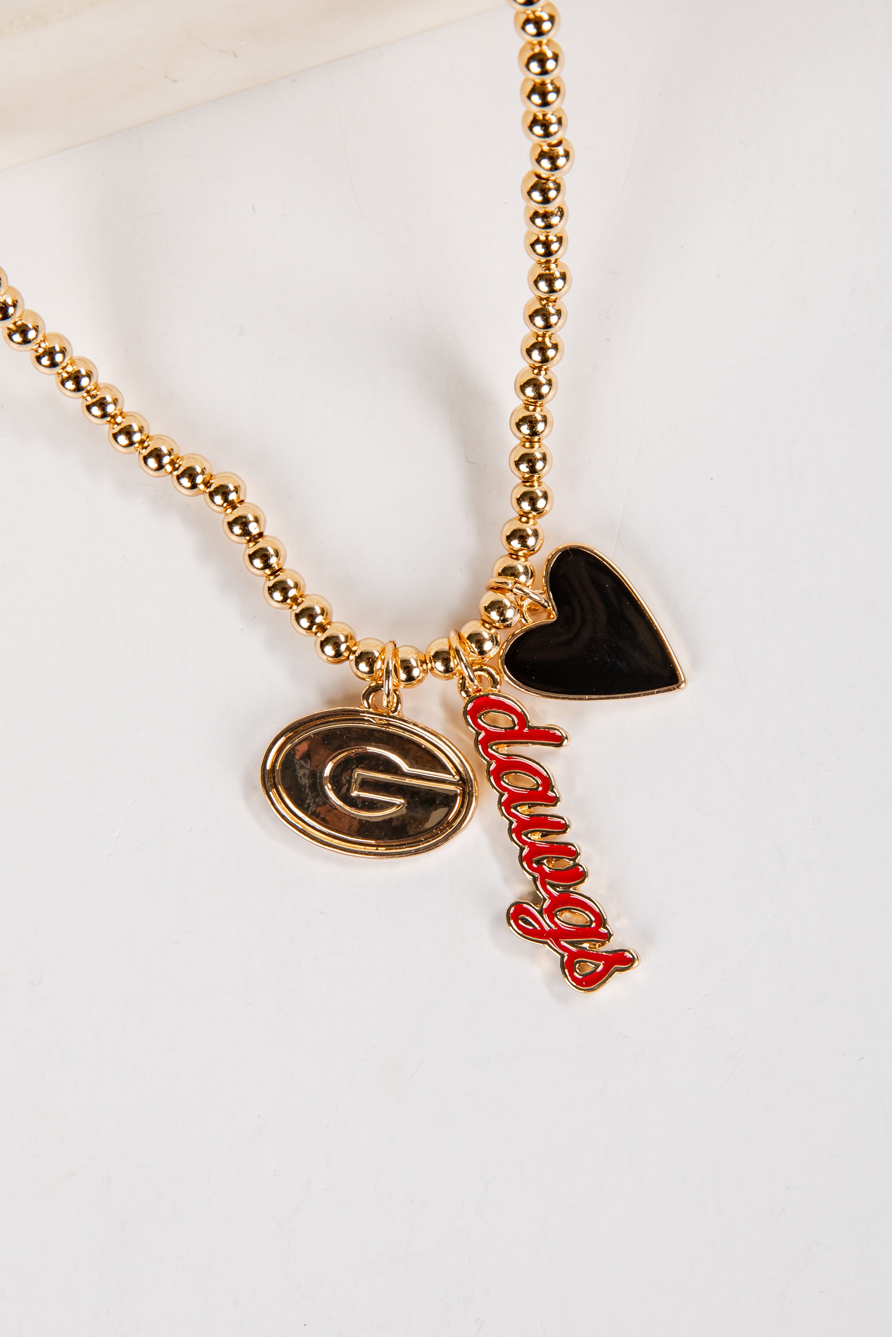 Necklace with gold beads, a heart-shaped black pendant, and red &