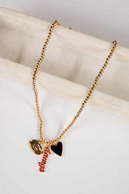 Gold necklace with heart and leaf pendants on a marble surface