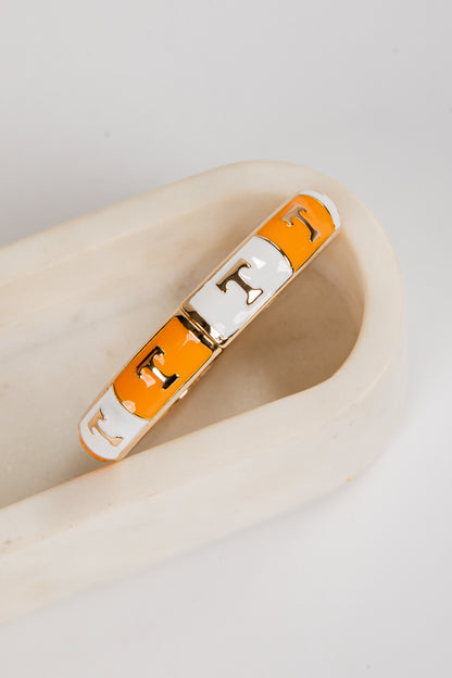 Bracelet with orange and white sections on a beige surface