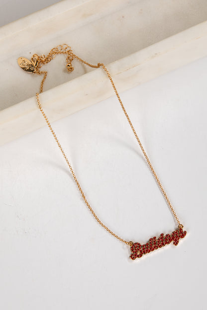 Gold necklace with red stones on a white surface