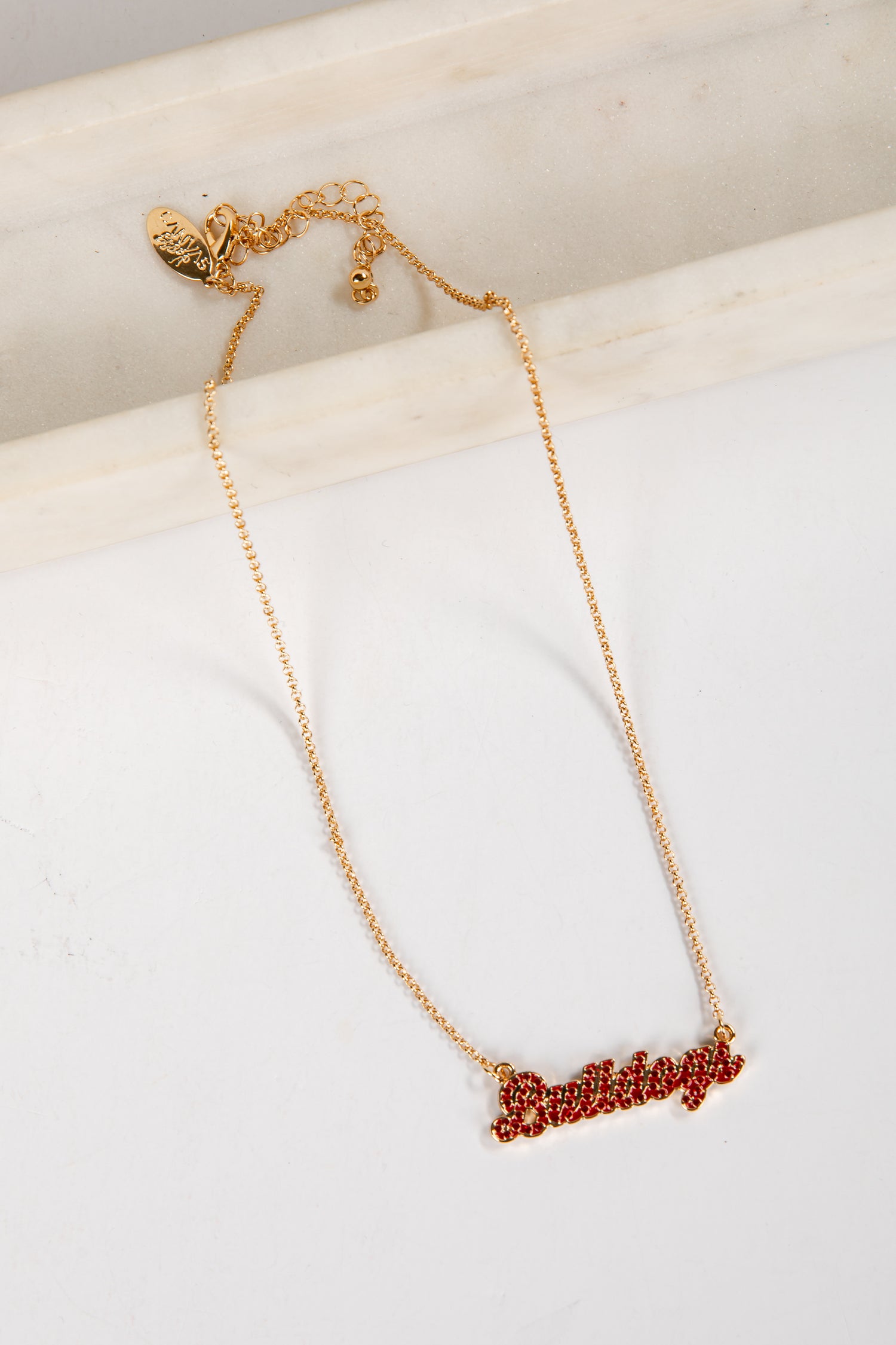 Gold necklace with red lettering on a white surface