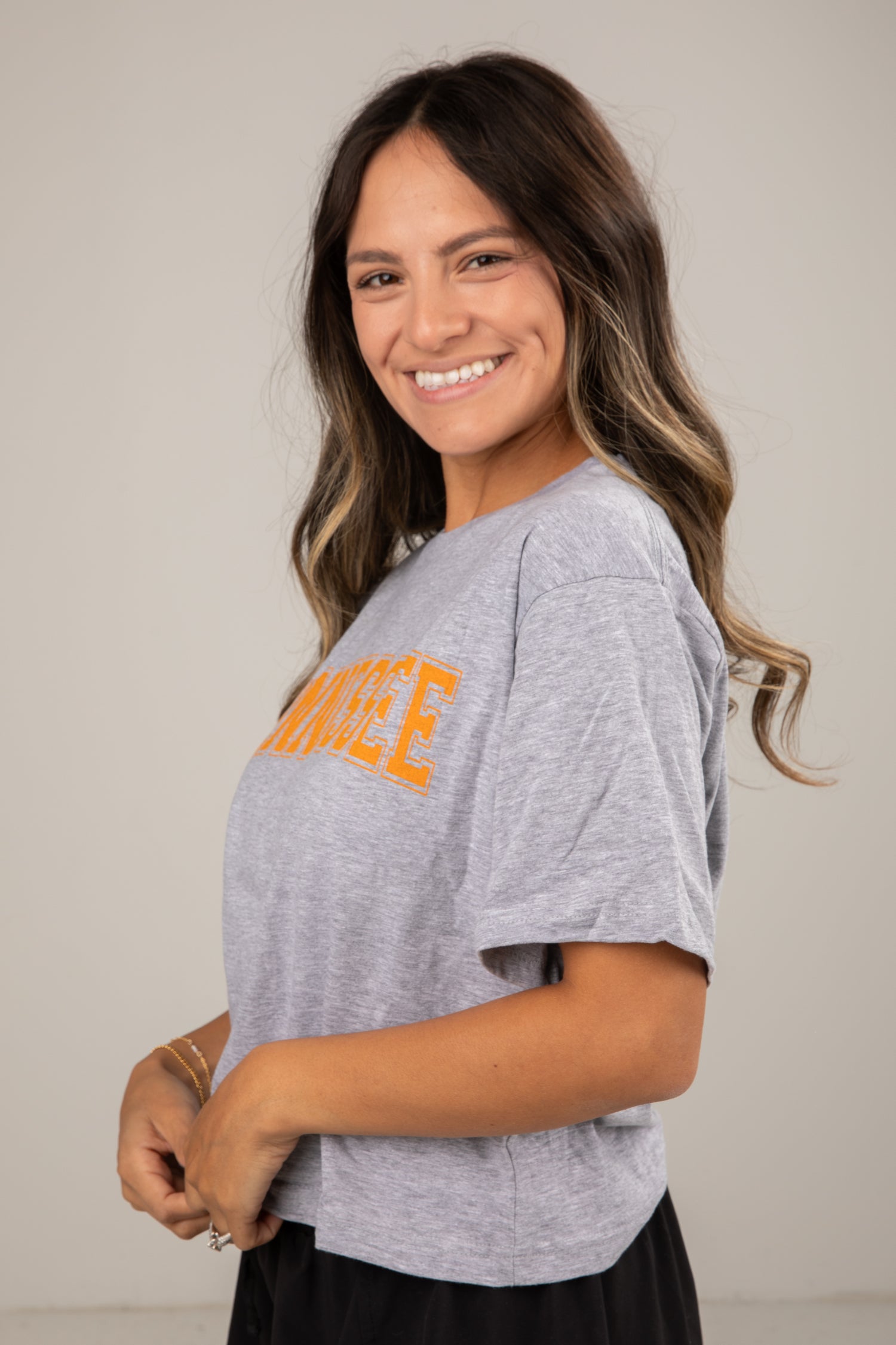 Woman wearing a gray t-shirt with orange text on a plain background