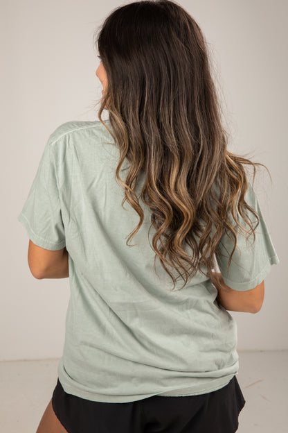 Woman wearing a light green t-shirt with a plain background