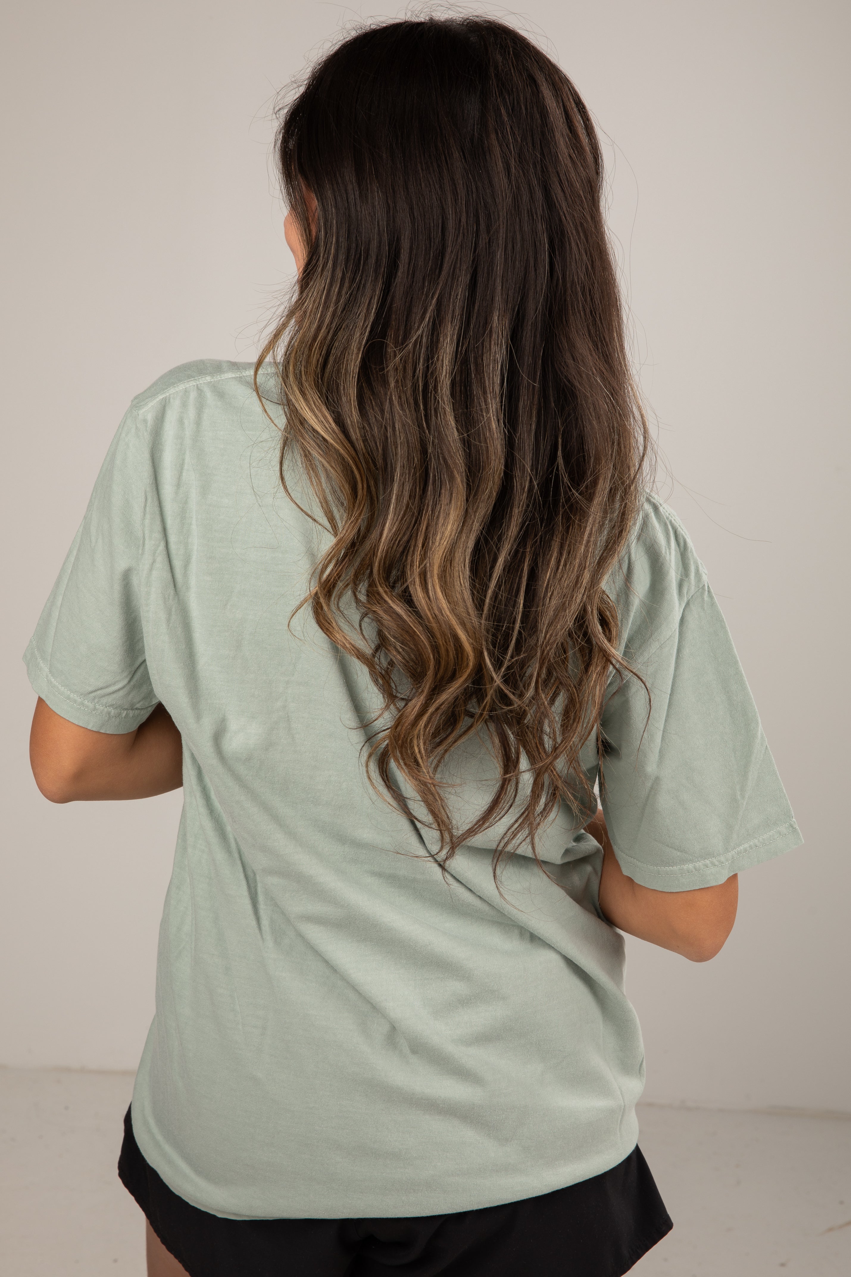 Person wearing a light green t-shirt against a plain background