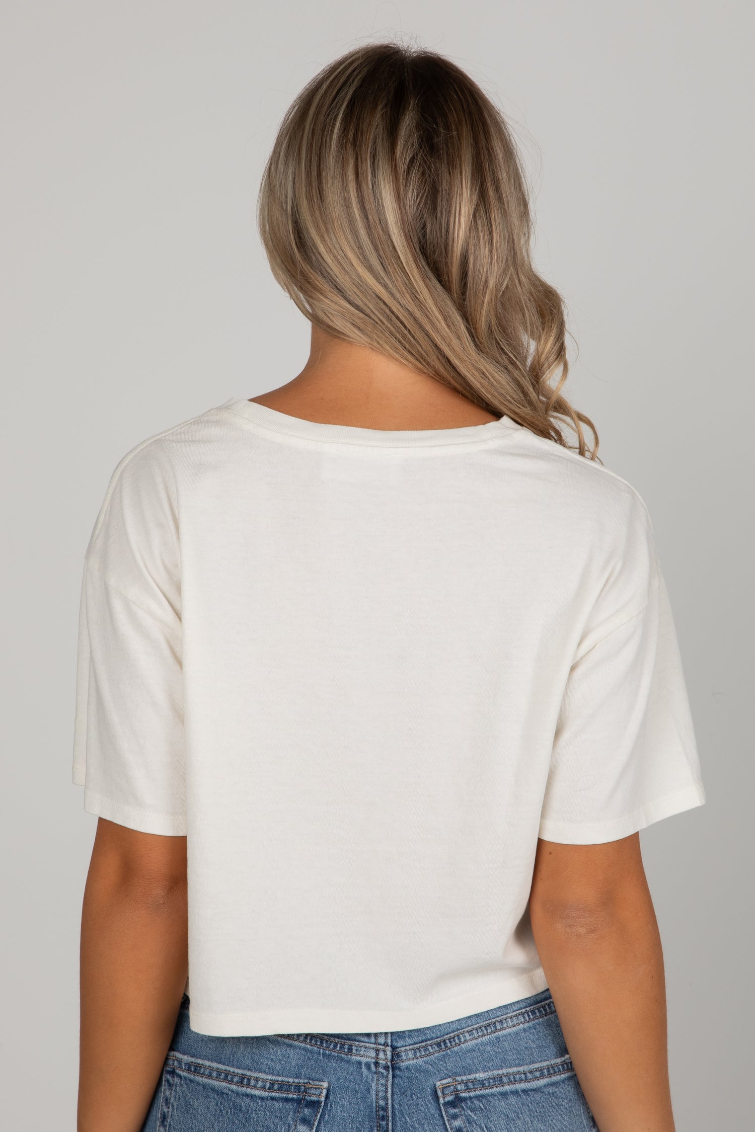 Person wearing a white t-shirt and blue jeans on a plain background