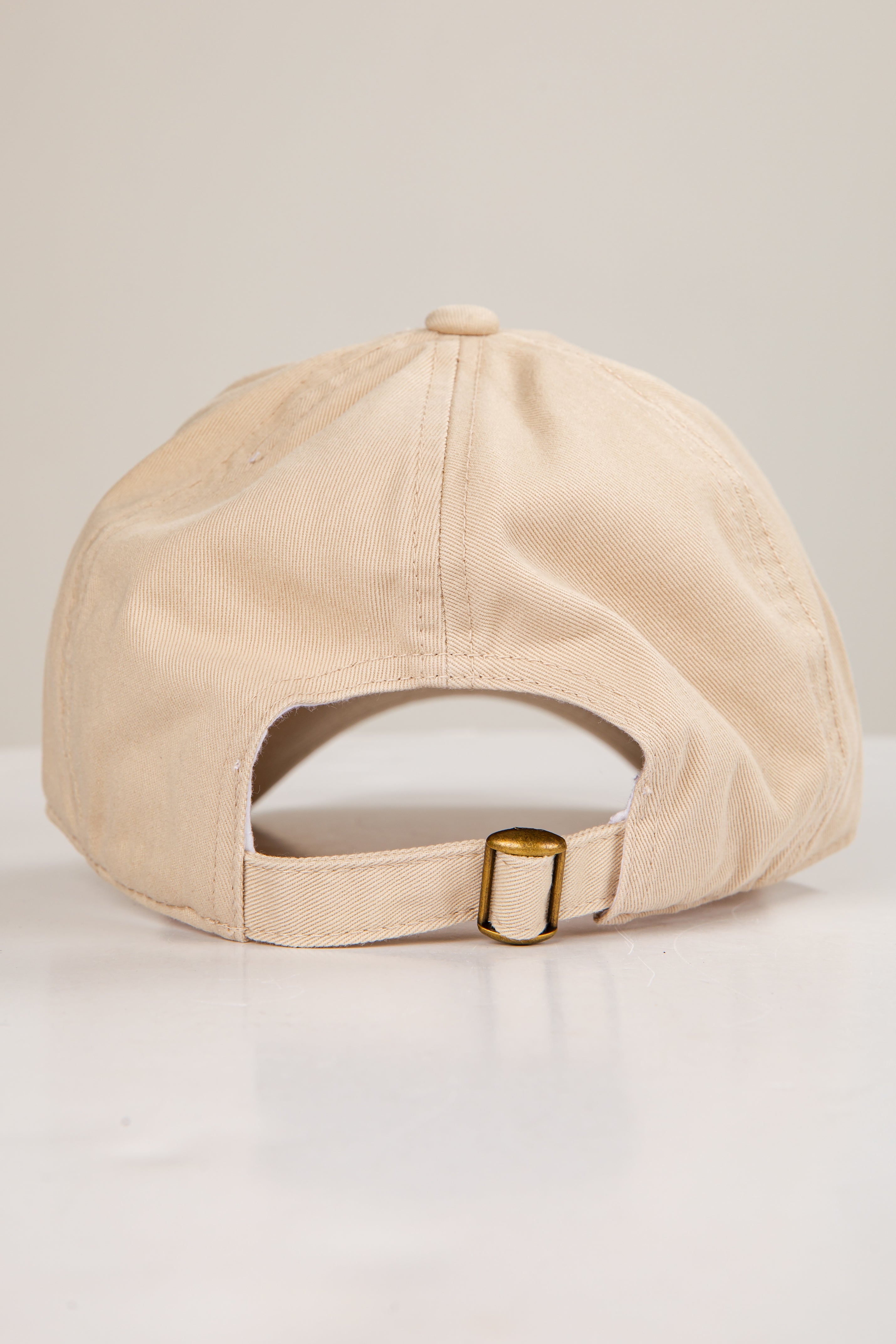 Beige cap with a gold buckle on a light gray background