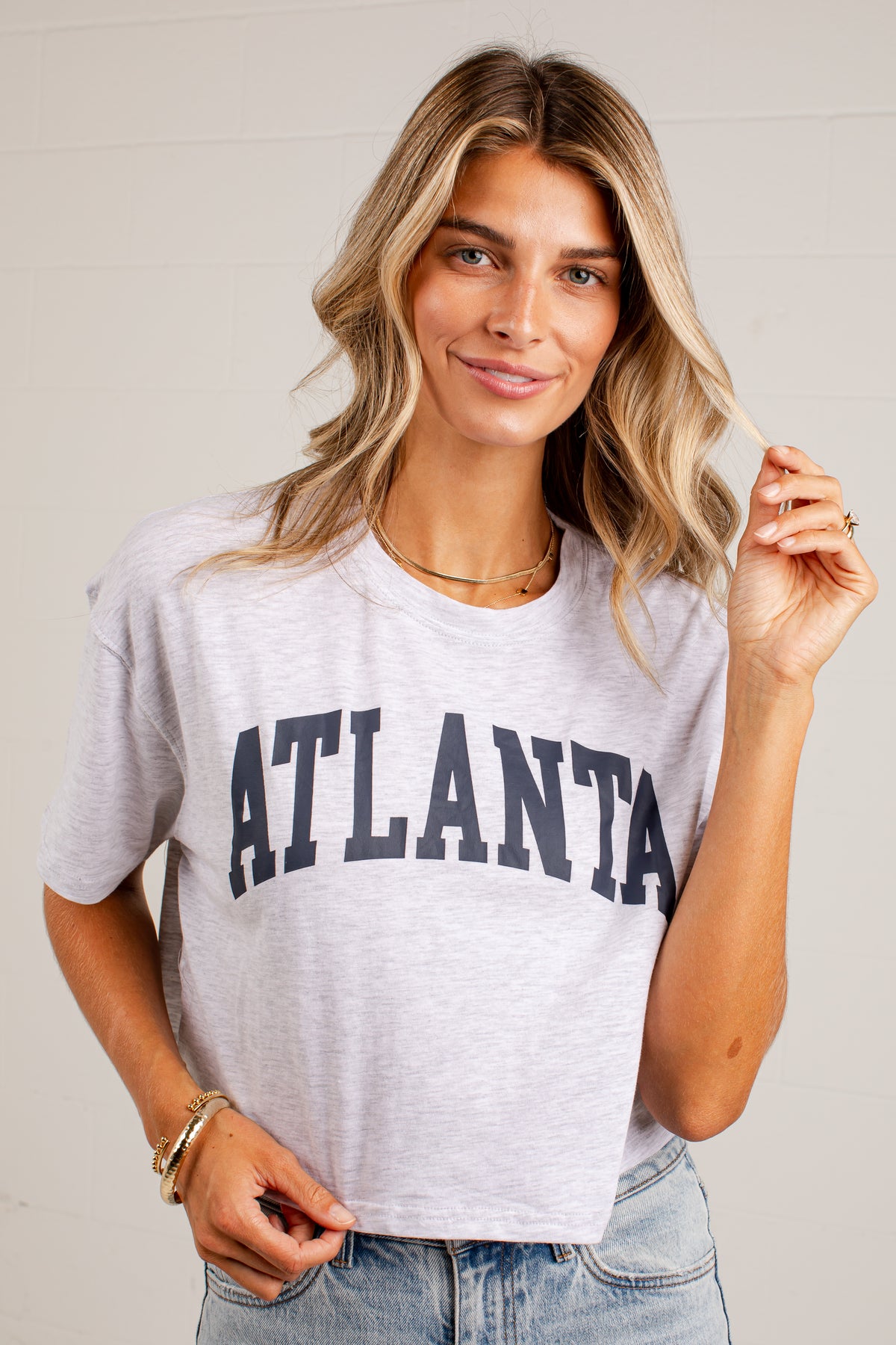 A woman wearing a light heather gray cropped t-shirt with &