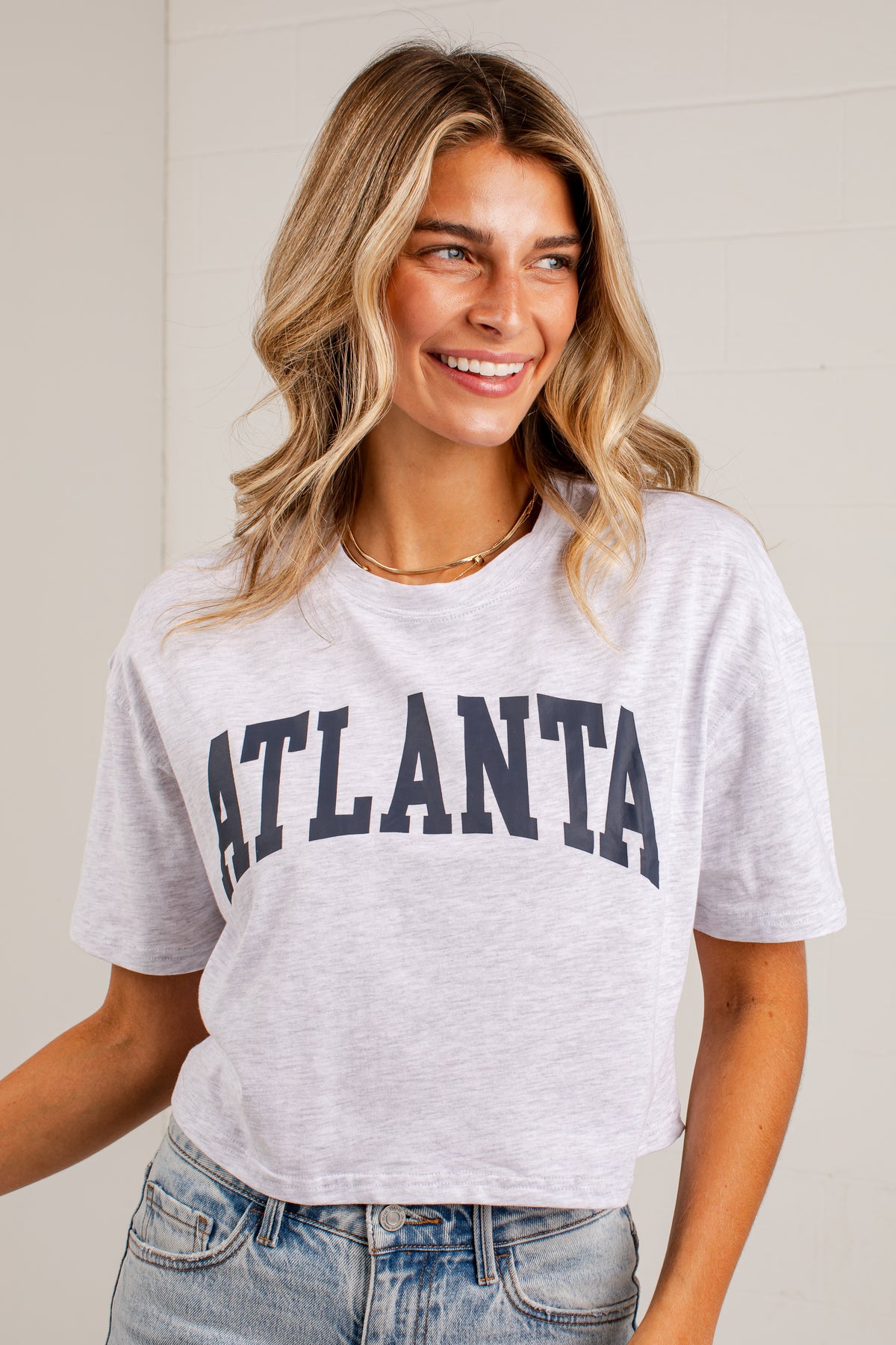 A woman wearing a light heather gray cropped t-shirt with &