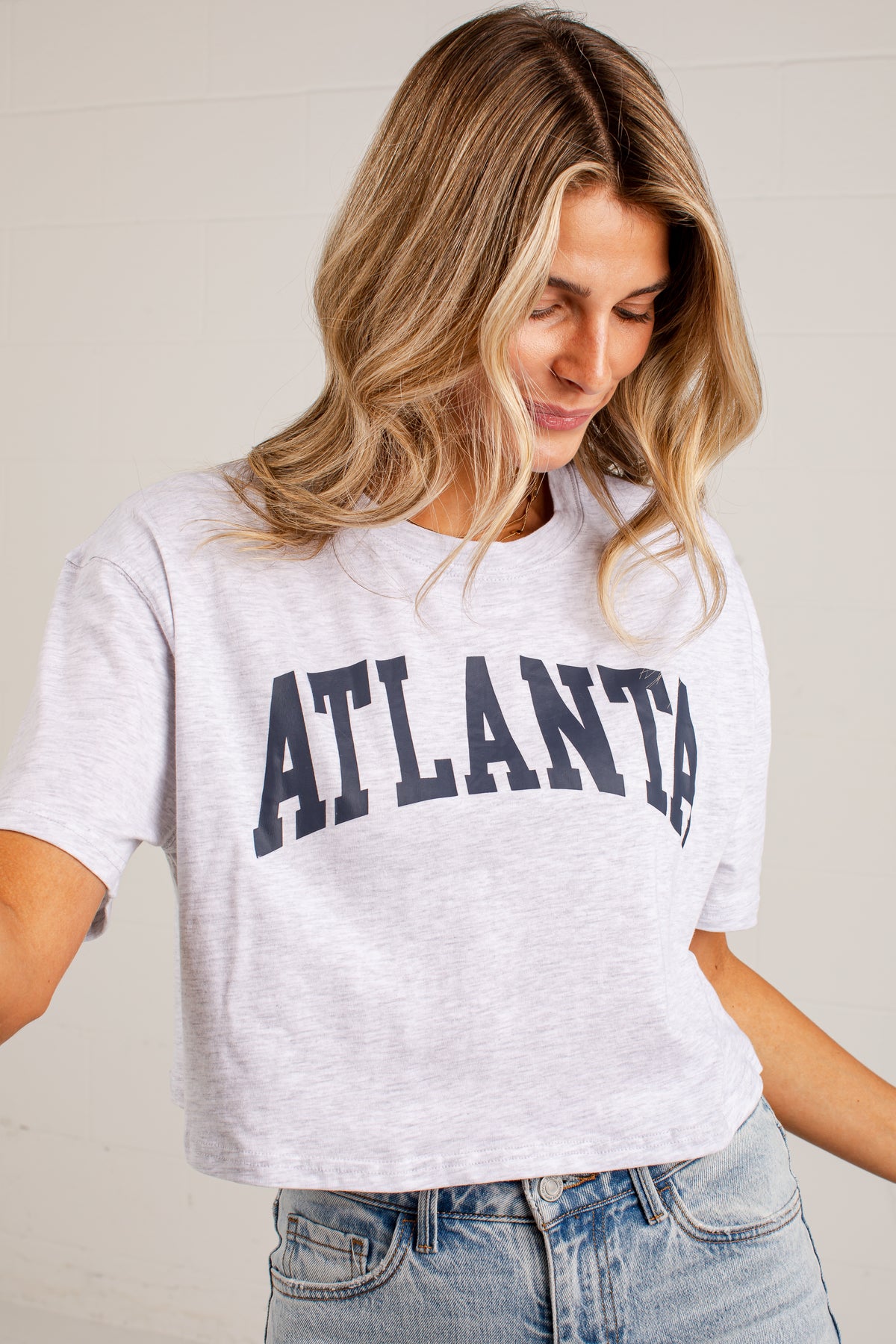 A woman wearing a light heather gray cropped t-shirt with &