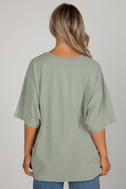 Person wearing a green oversized t-shirt on a plain background