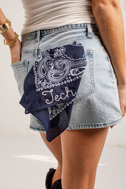 A navy blue bandana with a white paisley pattern and the word &