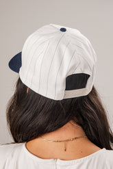 Person wearing a white and navy cap on a plain background