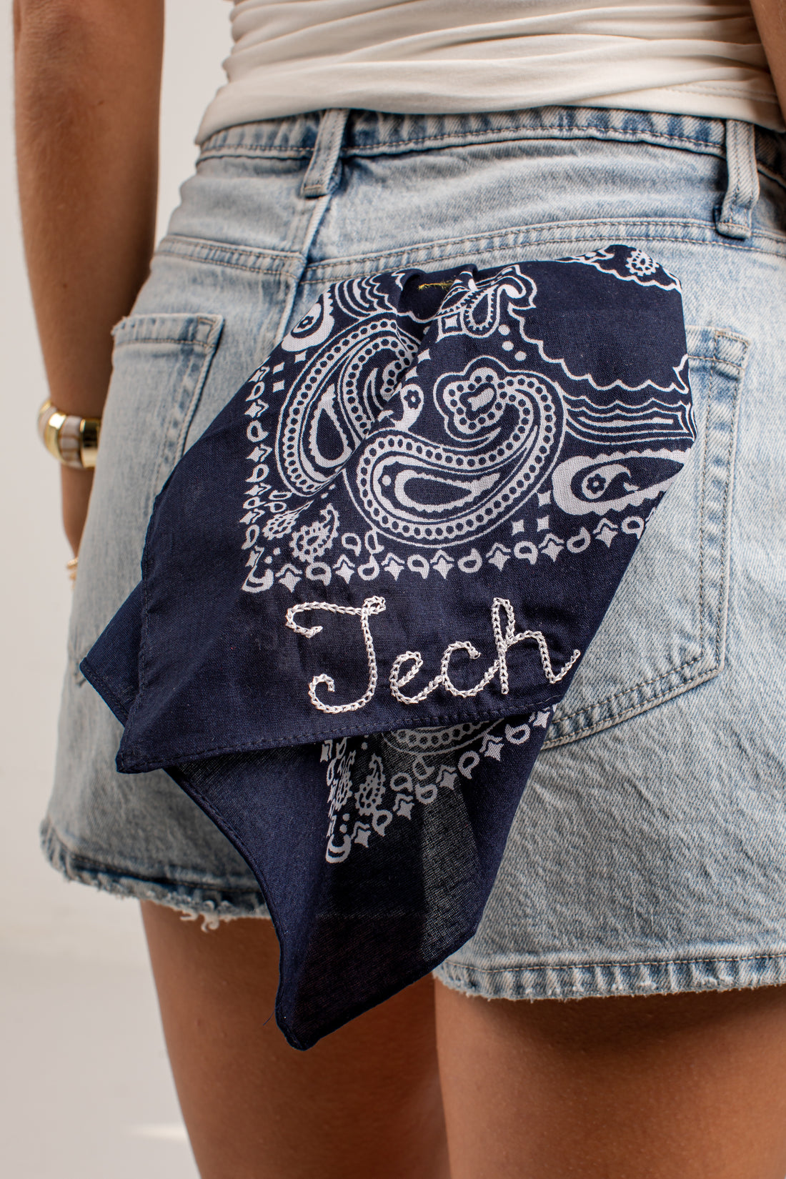 A navy blue bandana with a white paisley pattern and the word &
