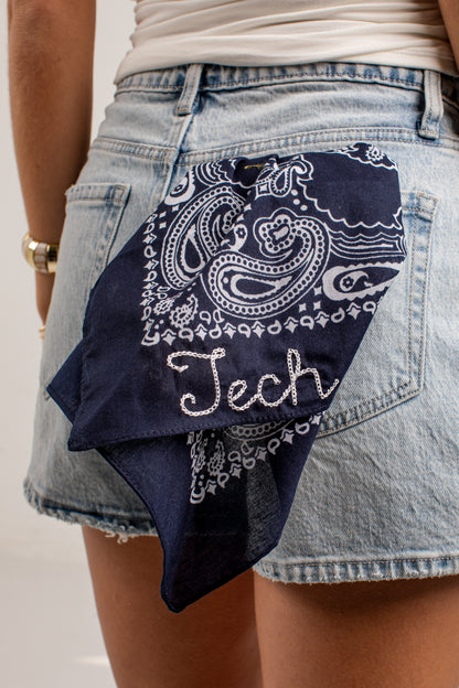 A navy blue bandana with a white paisley pattern and the word &