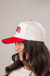 Person wearing a white cap with red brim and text on a gray background