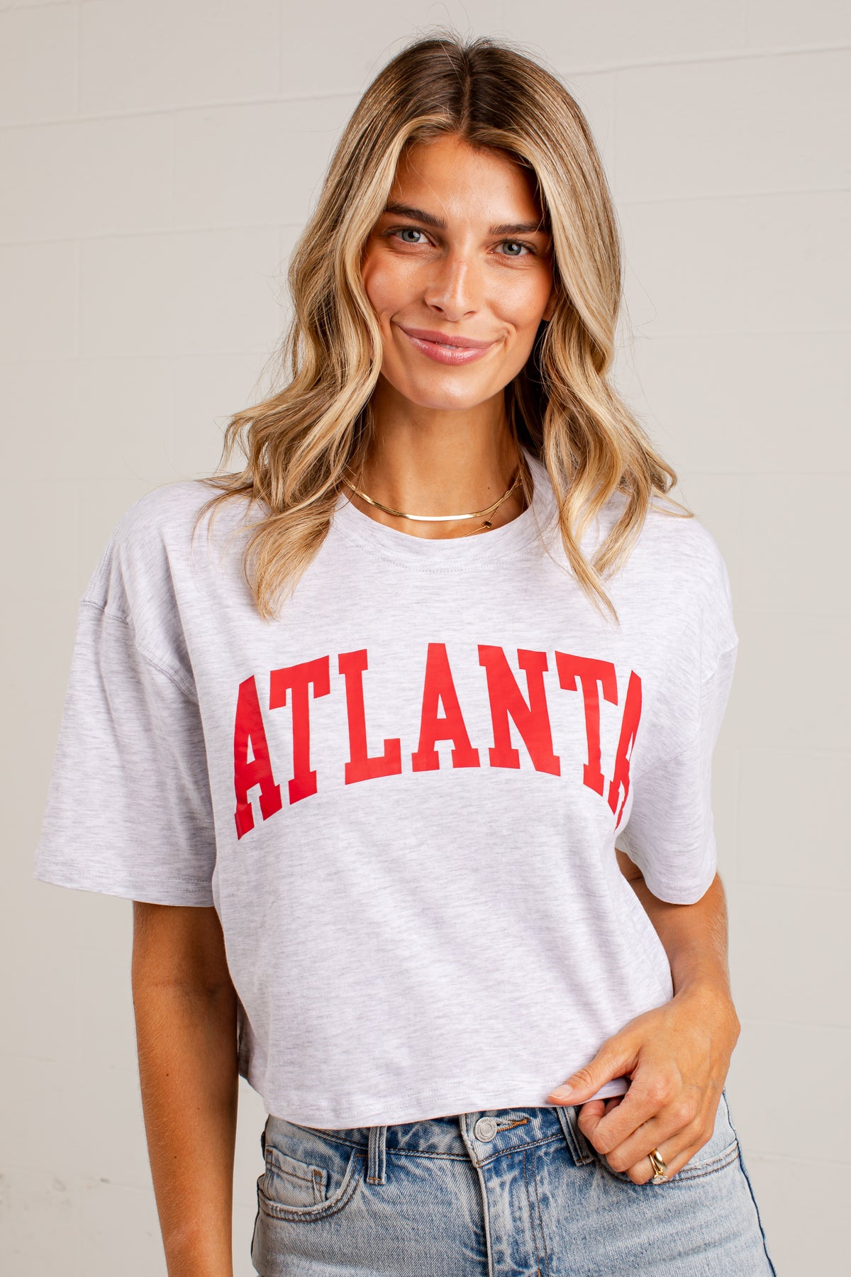 A woman wearing a light heather gray cropped t-shirt with &
