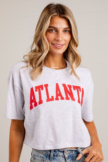 A woman wearing a light heather gray cropped t-shirt with &