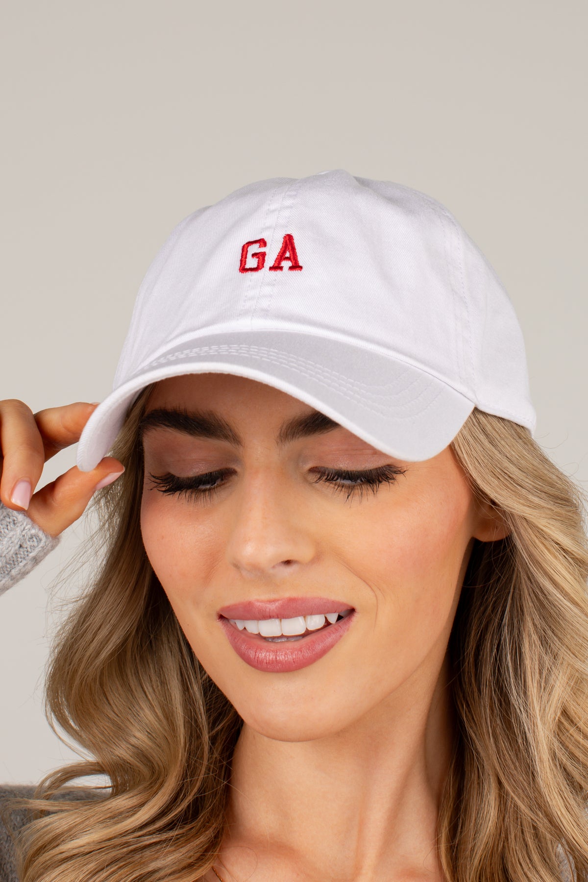 A woman wearing a white baseball cap with red embroidered letters &
