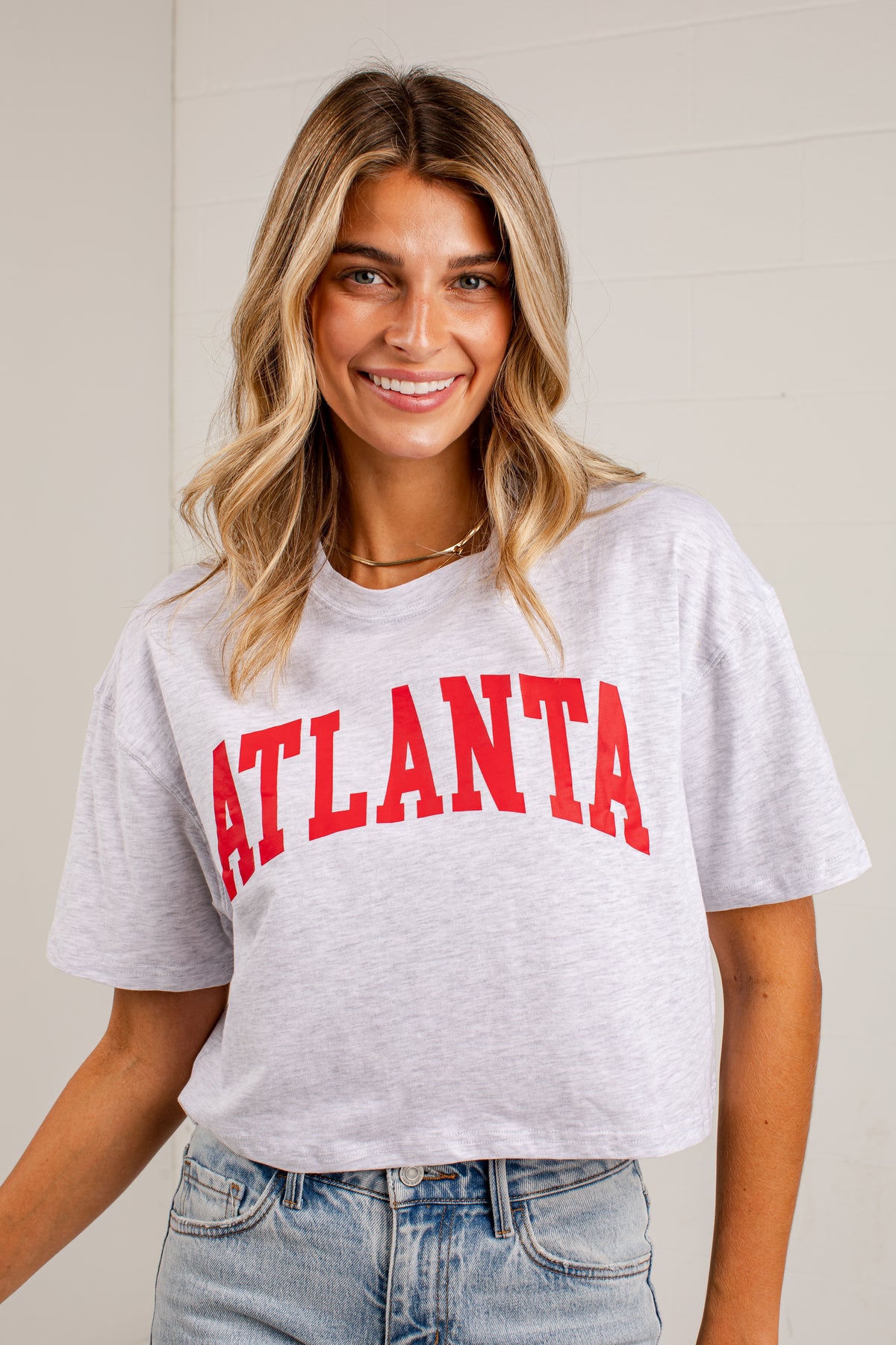 A woman wearing a light heather gray cropped t-shirt with &