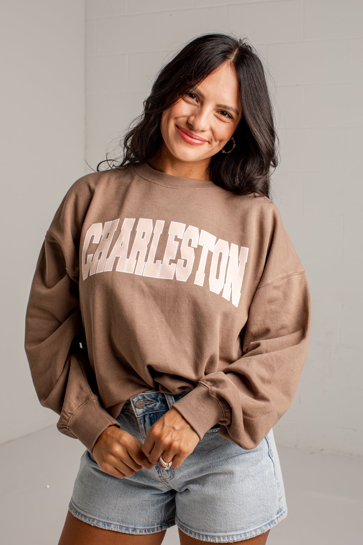 A woman wearing a brown oversized sweatshirt with &