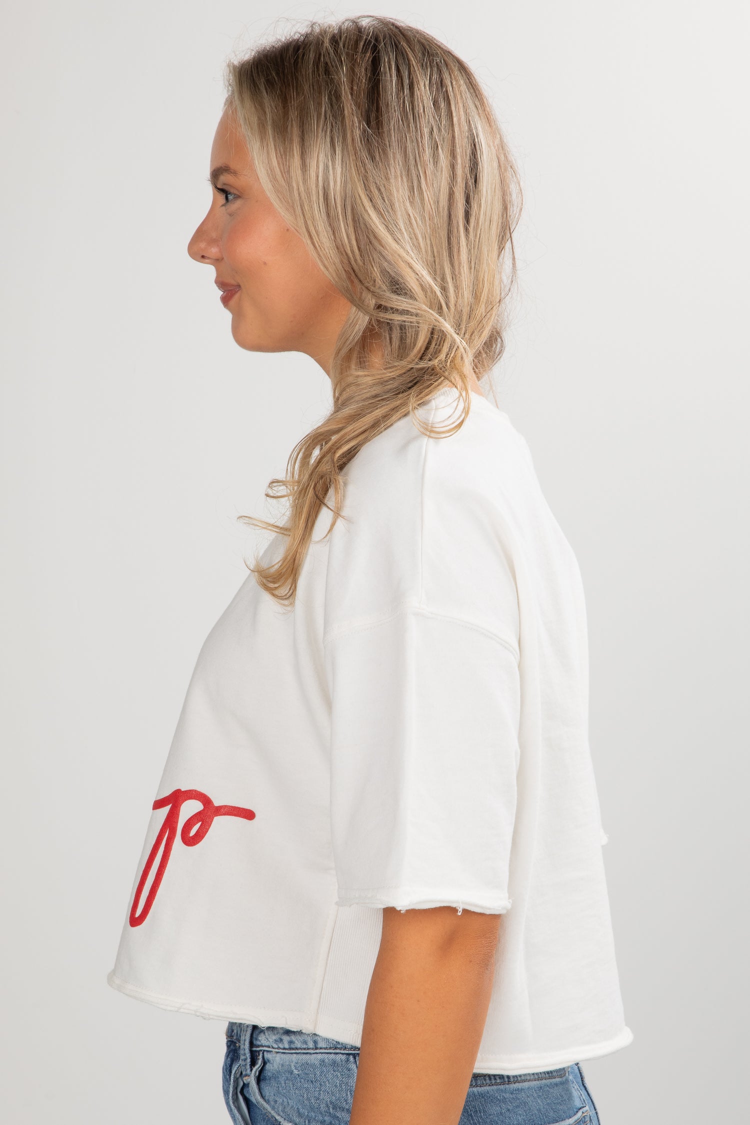 Woman wearing a white shirt with red text on a plain background