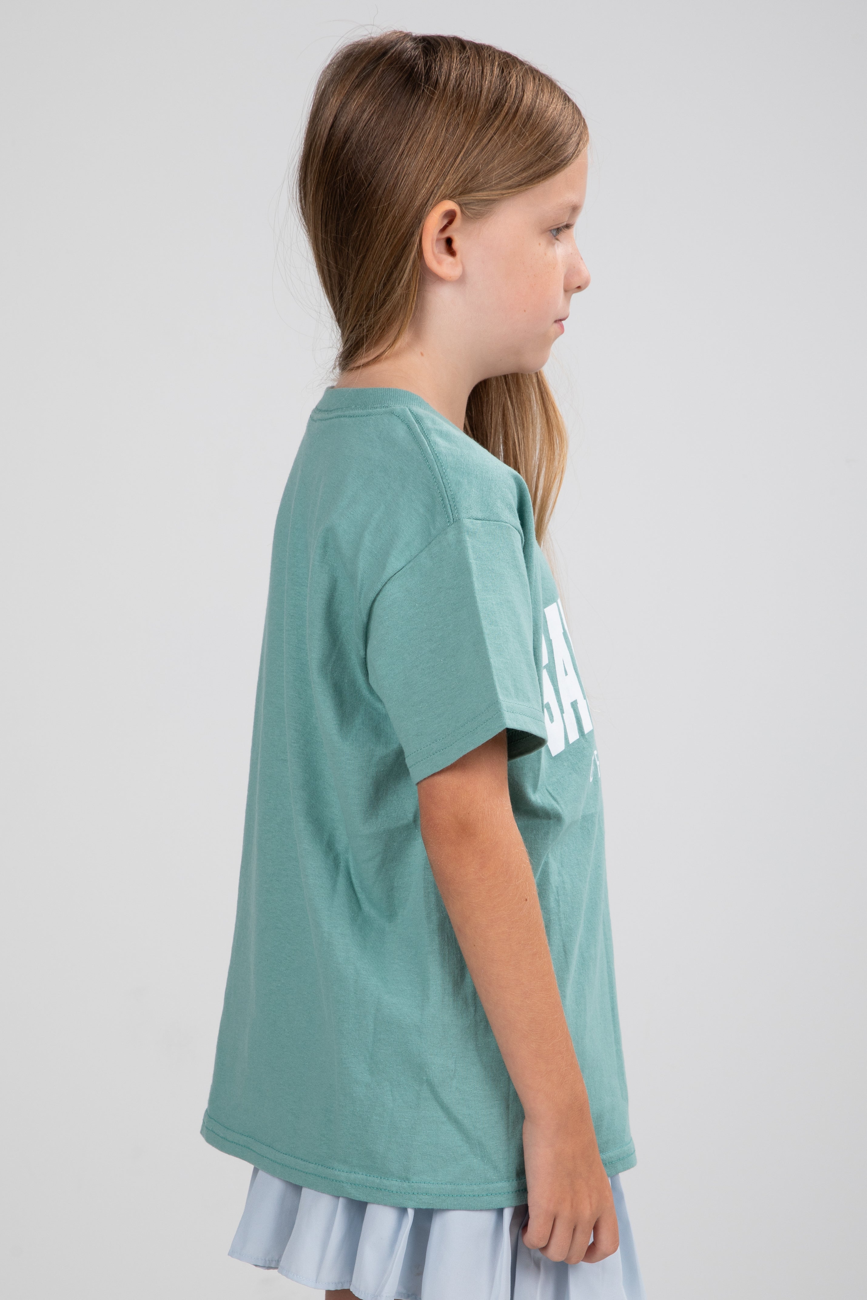 Young girl wearing a green t-shirt with text on a plain background
