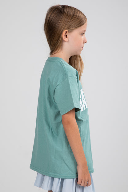 Young girl wearing a green t-shirt with text on a plain background