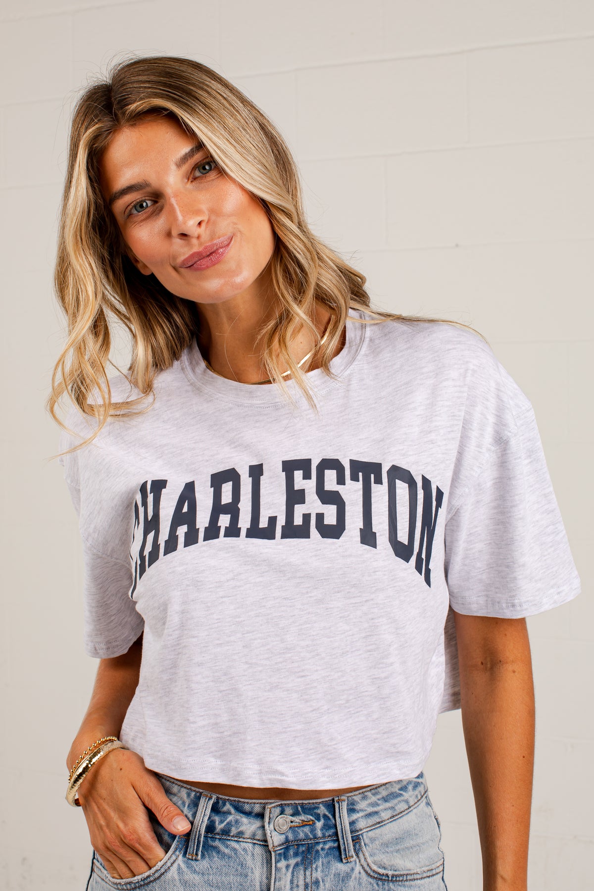 A woman wearing a light gray heather cropped t-shirt with &