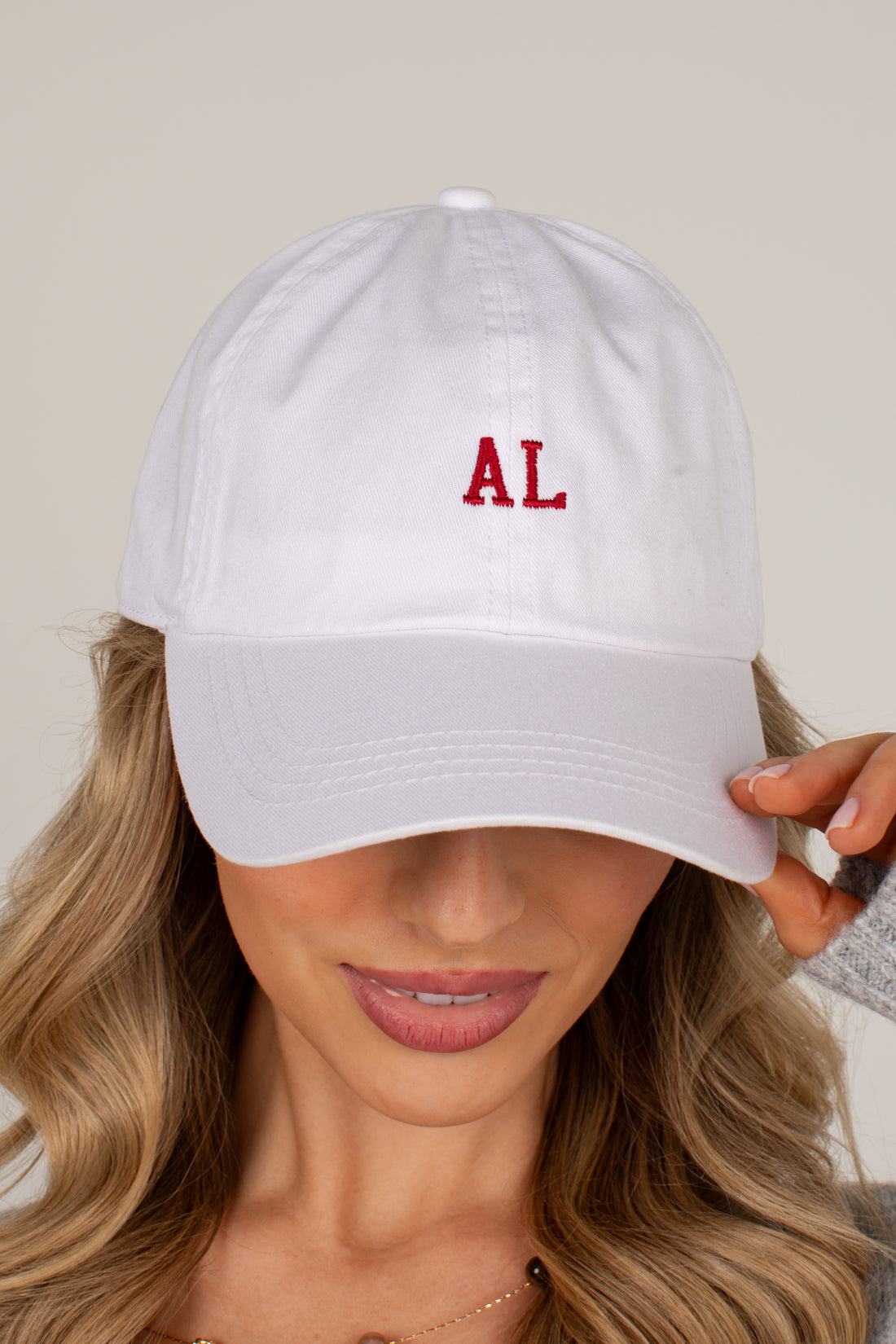 A woman wearing a white baseball cap with red embroidered letters &